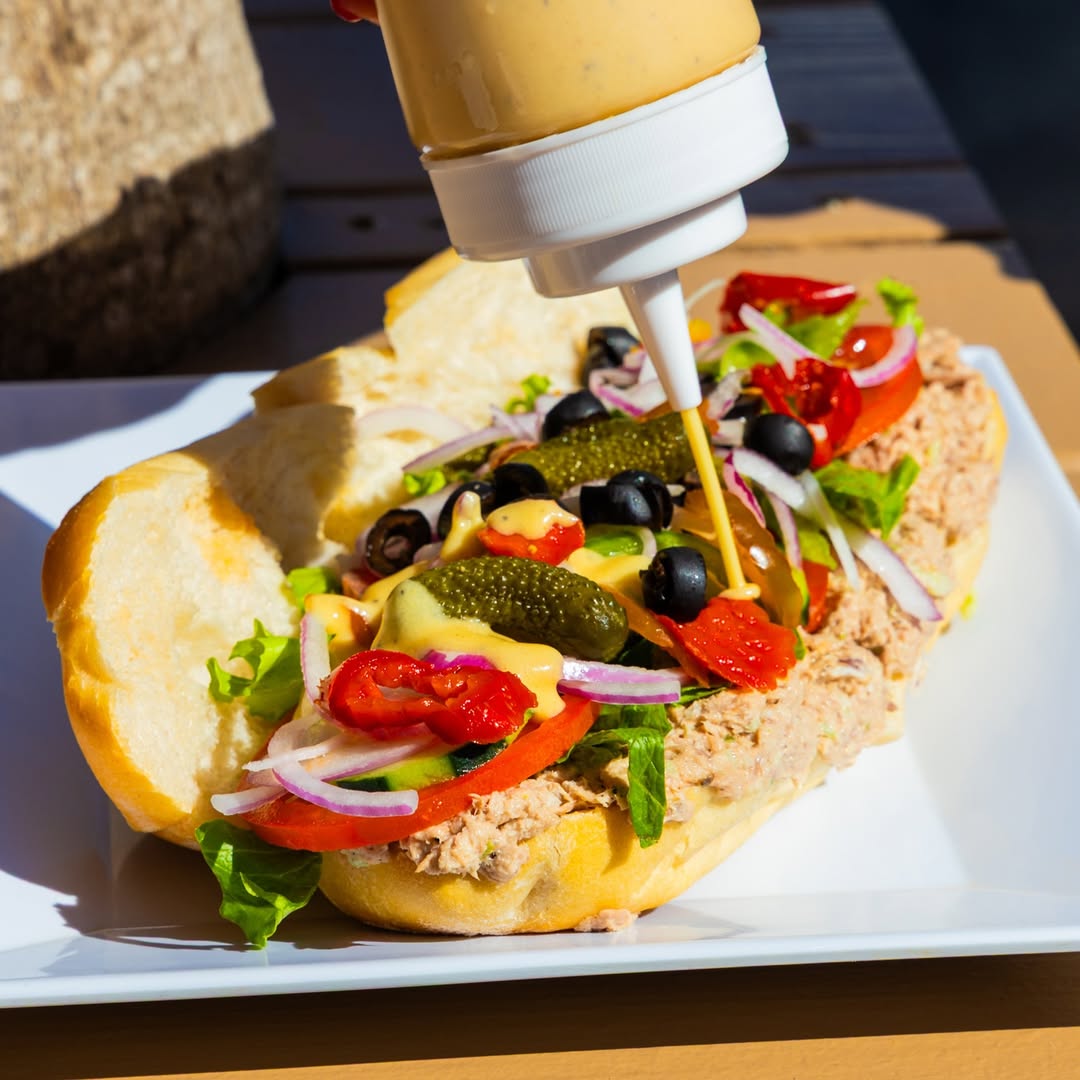 Pouring the signature Magic Sauce onto a freshly layered sandwich