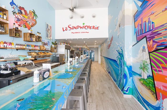 Interior of La Sandwicherie North Beach location with colorful wall art and counter seating