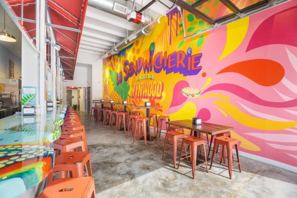 Interior seating area with colorful mural at La Sandwicherie Wynwood